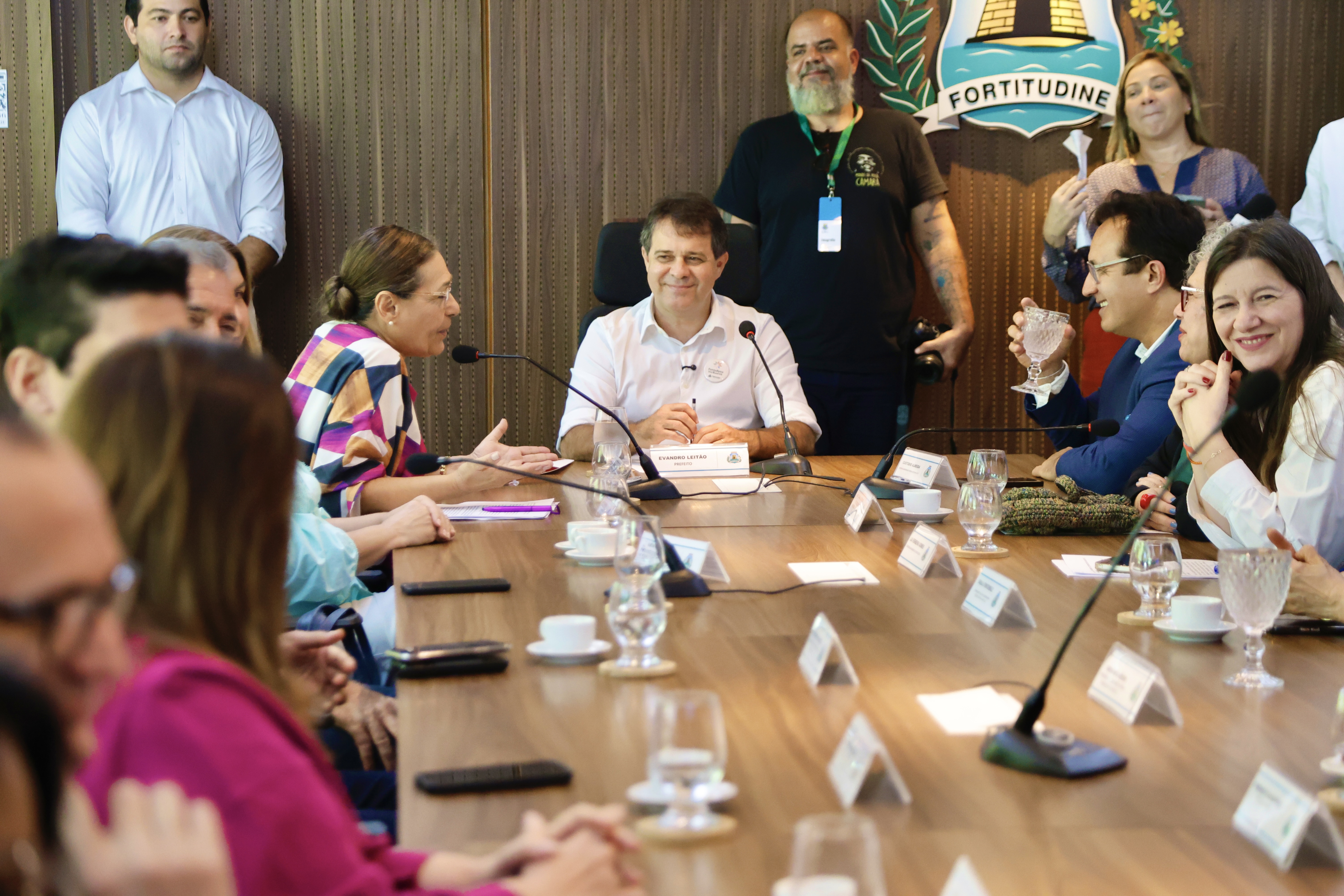 sala de reunião do paço municipal com um grupo de pessoas ao redor de uma mesa